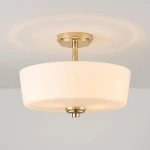 Lampa sufitowa Aspen z trzema gniazdami E27 w kolorze złotym i białym. Okrągły, matowy klosz z białego szkła, zawieszony na złotej podstawie, z delikatnym wykończeniem. Ujęcie z boku, pokazujące detale konstrukcji.