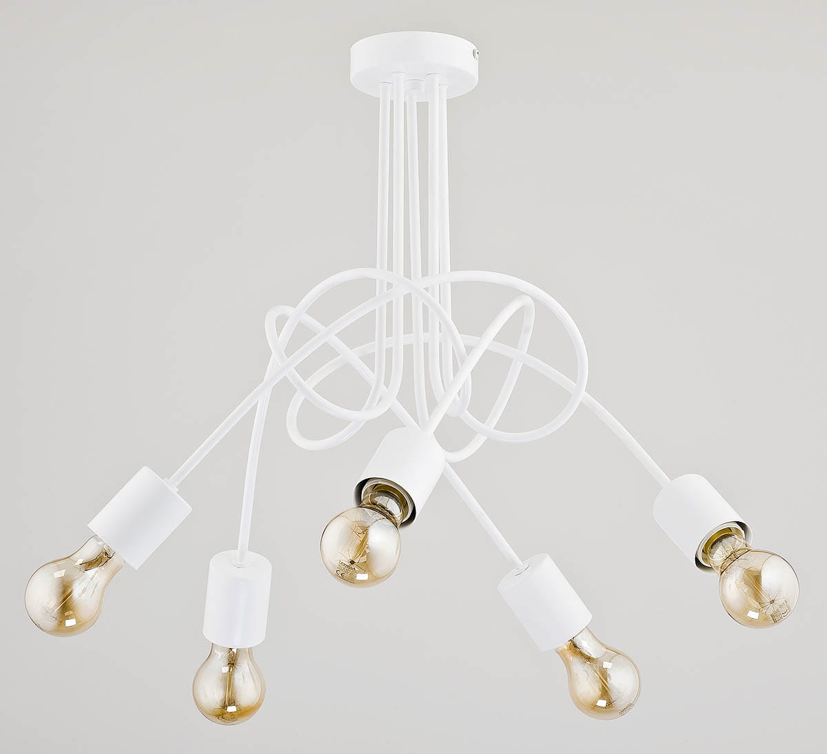 Lampa wisząca Tango 5-punktowa w białym kolorze z pięcioma żarówkami w przezroczystych oprawach. Kabelki rozmieszczone w artystyczny sposób. Ujęcie z góry, pokazujące detale konstrukcji i kształt lampy. Tło jednolite, jasne.