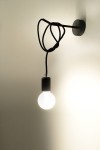 Kinkiet Edison 1-punktowy z czarnym kablem i oprawką. Żarówka w kulistym kształcie emitująca ciepłe światło, zawieszona na ścianie. Prosty, minimalistyczny design, zamontowany na gładkiej, jasnej ścianie.