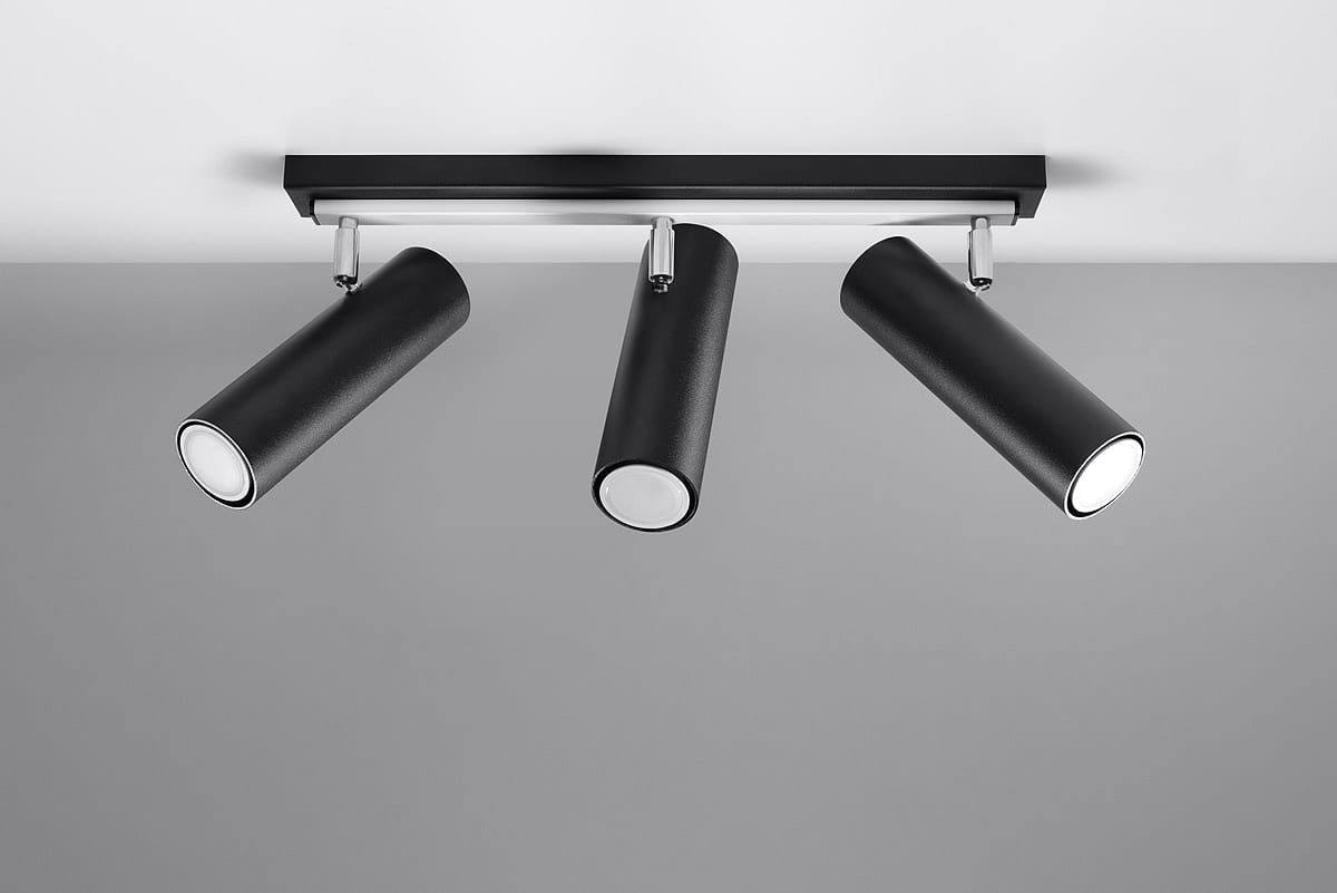 Lampa sufitowa 3-punktowa Direzione w kolorze czarnym. Składa się z trzech cylindrycznych reflektorów zamocowanych na metalowej szynie. Reflektory mają matową powierzchnię i okrągłe, białe szkło u góry. Ujęcie z góry, na jednolitym tle.