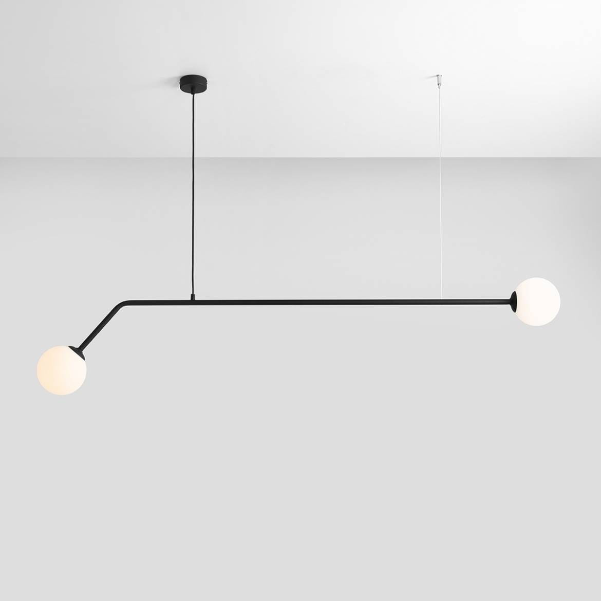 Czarna lampa wisząca 2-punktowa Pure 1064H1 z minimalistycznym, prostym kształtem. Posiada dwa okrągłe klosze w białym kolorze, zamontowana na cienkim, czarnym przewodzie. Produkt wiszący z sufitowym mocowaniem, umieszczony na jasnym tle.