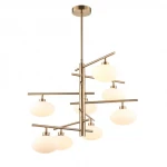 Lampa wisząca Fiorenzo 8-punktowa w kolorze mosiądzu z białymi, matowymi kloszami. Konstrukcja z metalowych prętów w nowoczesnym stylu, zawieszona na długim stelażu. Ujęcie frontalne, w całości widoczna.