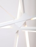 Biała lampa wisząca Spider LED o trzech punktach świetlnych. Zbliżenie na strukturę lampy z geometrycznymi kształtami i wbudowanym oświetleniem LED. Elementy są matowe, a światło emituje się z wąskich szczelin. Tło jasne, minimalistyczne.