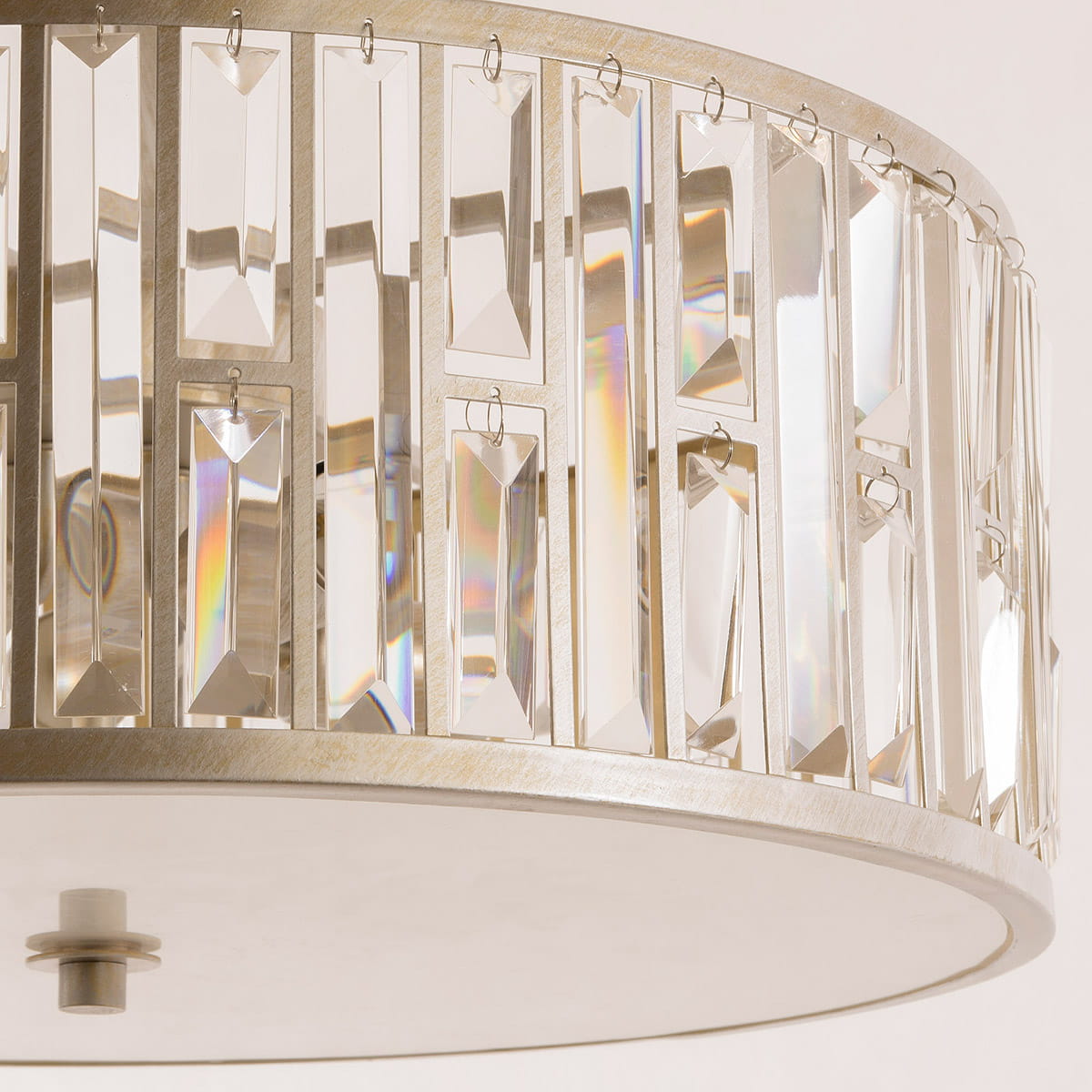 Lampa wisząca Moscow 5-punktowa z metalowym stelażem w kolorze srebrnym. Klosz ozdobiony przezroczystymi, wielokątnymi kryształkami, które odbijają światło, tworząc efektowną iluminację. Ujęcie z boku, ukazujące detal wykonania.