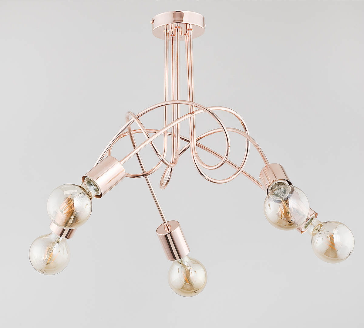 Lampa wisząca Tango w kolorze miedzi z pięcioma punktami świetlnymi. Konstrukcja z metalowych, skręconych elementów. Widoczne przezroczyste żarówki w kulistych oprawach. Ujęcie z góry, wisząca, na jednolitym tle.