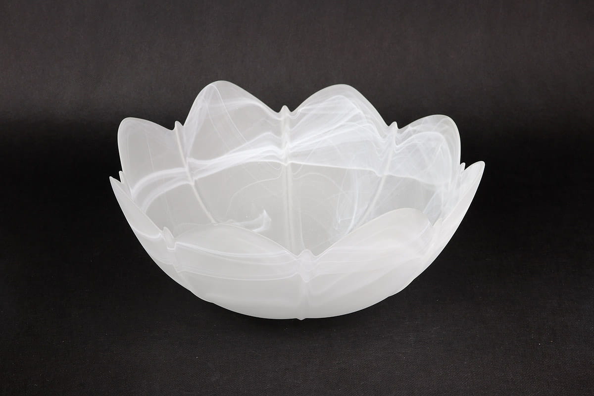 Klosz szklany Fuks D300 w kolorze alabastrowym, o kształcie przypominającym kwiat, z lekko przezroczystą powierzchnią. Produkt widoczny z boku, stojący na płaskiej powierzchni, z falistymi brzegami i gładką fakturą.