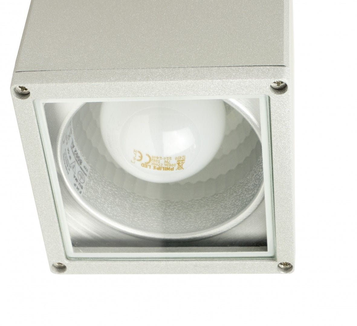 Lampa sufitowa elewacyjna Adela 1-punktowa w kolorze aluminium 8003. Kwadratowa obudowa z przezroczystym szkłem, widoczna żarówka LED wewnątrz. Ujęcie z góry, pokazujące fakturę materiału i detal montażowy.