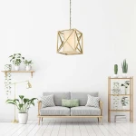 Lampa wisząca New York w geometrze sześcianu, w kolorze złotym, z białym kloszem, zawieszona na łańcuchu. Otoczona roślinami w doniczkach, umieszczona w nowoczesnym wnętrzu z jasnymi ścianami i drewnianymi meblami.