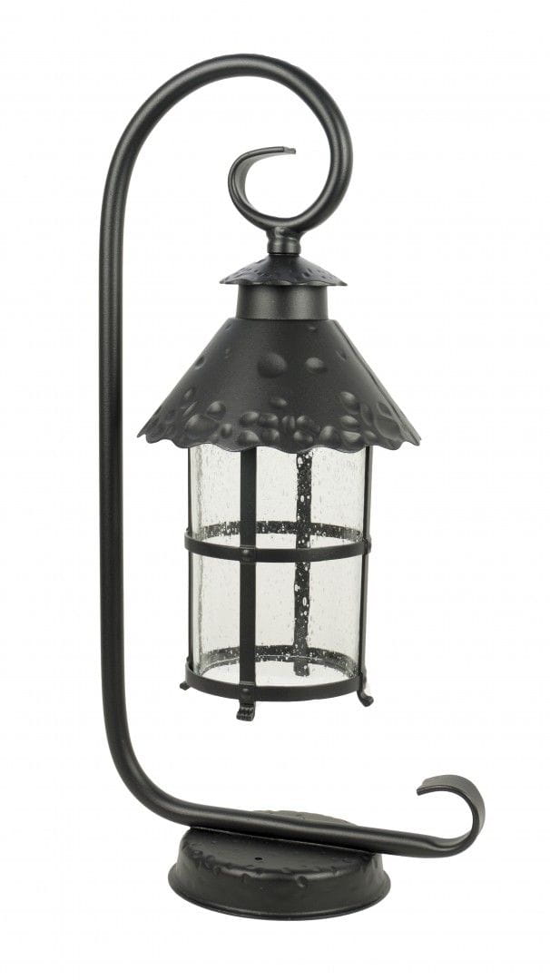 Lampa stojąca ogrodowa Toledo w kolorze czarnym, z metalowym, dekoracyjnym kloszem i szklanym, przezroczystym wnętrzem. Ujęcie z boku, z wygiętą podstawą i ozdobnym uchwytem. Widoczne detale konstrukcyjne i struktura klosza.