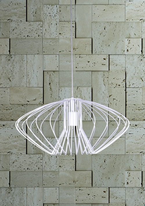 Lampa wisząca Tizi D52 w kolorze białym, o nowoczesnym, ażurowym kształcie, zawieszona na cienkim przewodzie. Widoczny metalowy stelaż w formie otwartej konstrukcji, umieszczony na tle kamiennej ściany.