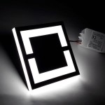 Oprawa schodowa LED 230V o barwie zimnej 6500K, kwadratowa, z czarną ramką i podświetleniem w formie prostokątów. Widoczny zasilacz z przewodami. Ujęcie frontalne, podkreślające minimalistyczny design.