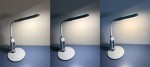 Lampka biurkowa Mida LED 1-punktowa w kolorze białym, z elastycznym ramieniem i okrągłą podstawą. Włącznik z niebieskim podświetleniem, zbliżenie na kluczowe detale. Produkt ustawiony na równym tle, oświetlenie skierowane w górę.
