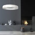 Biała lampa wisząca Reus LED LP-8069/1P w kształcie pierścienia, zawieszona nad minimalistycznym wnętrzem z ciemnym tłem i kominkiem. Prosta konstrukcja, nowoczesny design, idealna do aranżacji przestrzeni.