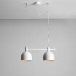 Beryl lampa wisząca 2-punktowa w kolorze białym, z dwoma okrągłymi kloszami zawieszonymi na cienkim, prostokątnym stelażu. Lampa wisząca jest zamontowana pod sufitem, z widocznymi przewodami elektrycznymi. Tło w jasnoszarym kolorze.