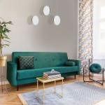 Lira LED lampa wisząca 3-punktowa, w kolorze białym, zawieszona na cienkich linkach, nad zieloną sofą. W tle zasłony w roślinny wzór oraz stolik kawowy z książkami. Świetne oświetlenie dla nowoczesnych wnętrz.