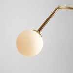 Lampa wisząca 2-punktowa w kolorze złotym z dwiema kulistymi kloszami w odcieniu mlecznym. Kształt prosty, z metalowym ramieniem, zawieszona pod kątem. Tło jasnoszare, minimalistyczne.