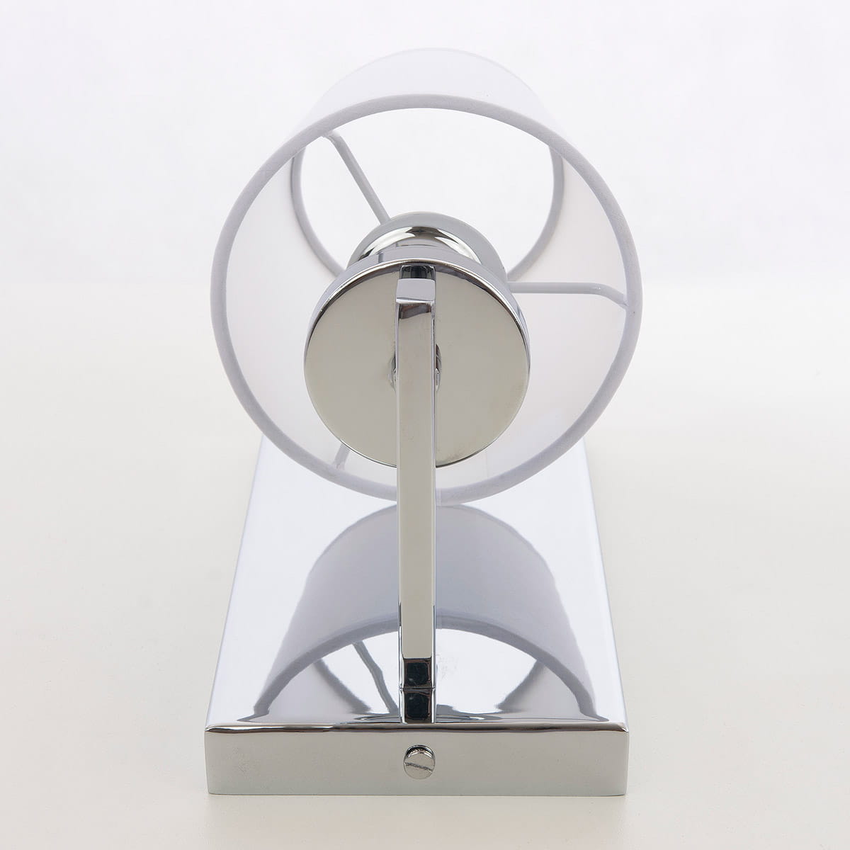 Kinkiet London 1-punktowy w kolorze chromu i białym, z przezroczystym kloszem o okrągłym kształcie. Ujęcie frontalne, produkt zamontowany na prostokątnej podstawie. Widoczny metalowy uchwyt oraz dekoracyjne detale.