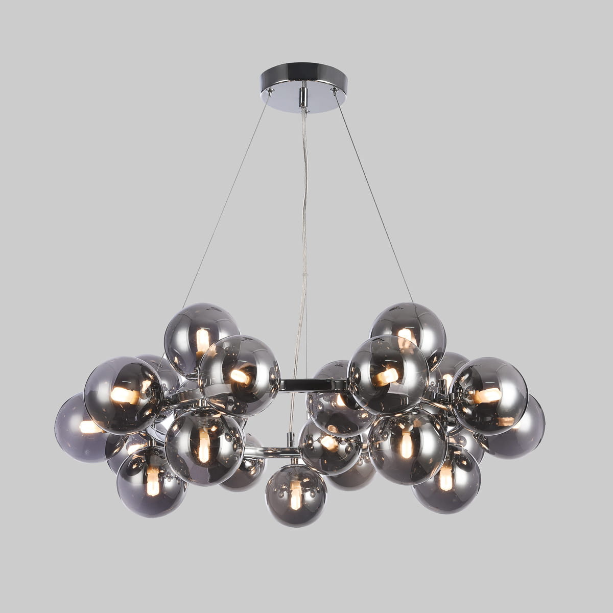 Lampa wisząca Cabella 25-punktowa z dymionymi kulami. Wykonana z materiałów metalowych i szklanych, w kolorze chromu i dymionym szkle. Zawieszona na cienkich linkach, z centralnym mocowaniem. Kule rozmieszczone w chaotyczny sposób, emitujące światło.
