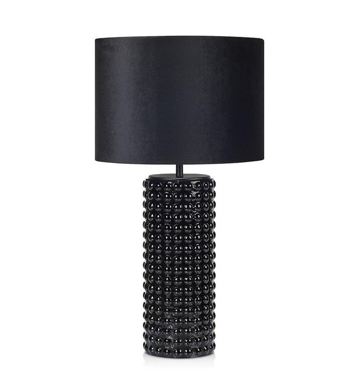 Czarna lampa stołowa Proud z 1 punktem świetlnym. Okrągły, teksturowany korpus z wypukłymi kulkami, zakończony cylindrycznym kloszem z matowego materiału. Ujęcie frontalne, stojąca na płaskiej powierzchni.