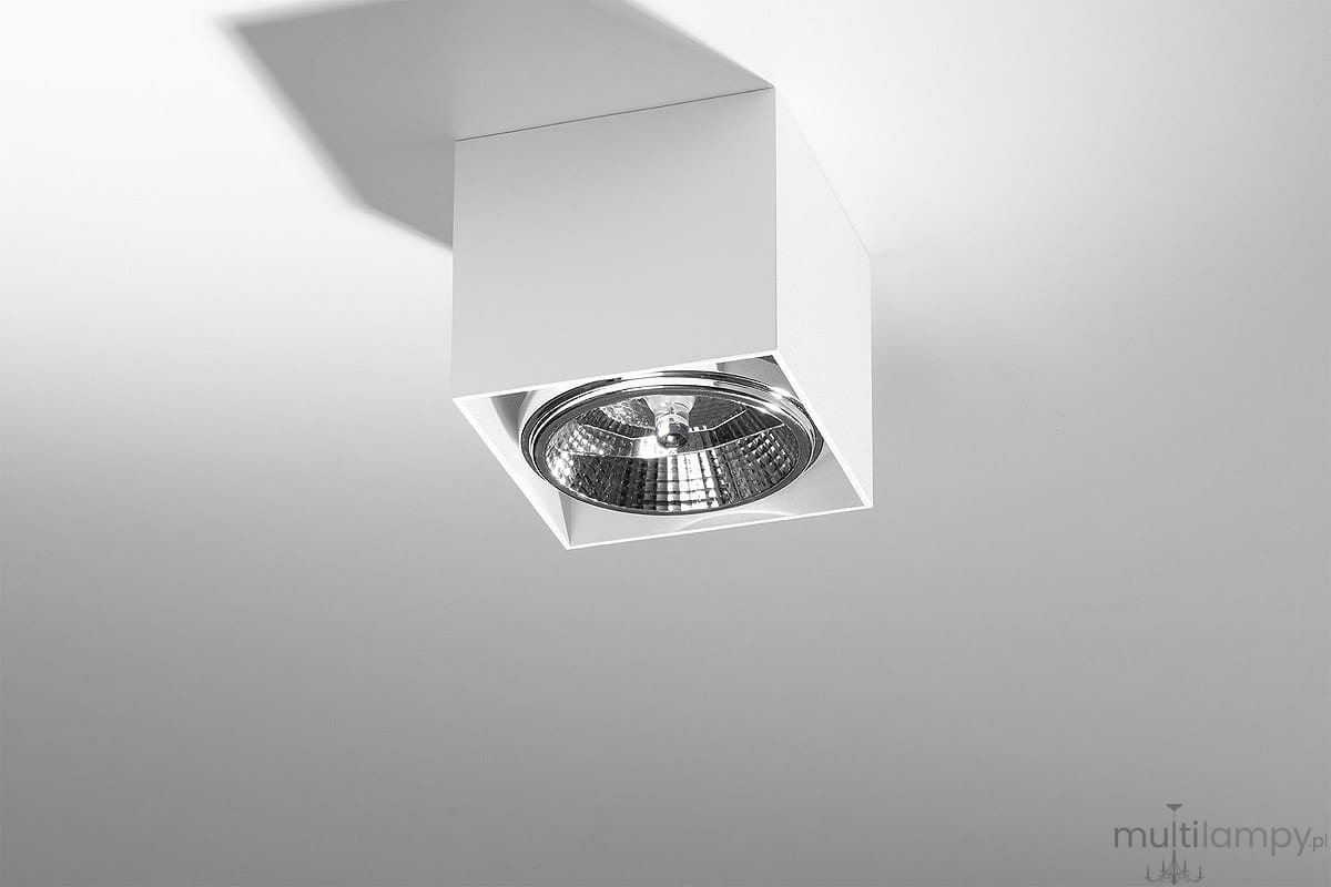 Biała lampa sufitowa Blake, 1-punktowa, montowana w sposób wiszący. Kwadratowa obudowa z metalicznym reflektorem wewnętrznym, umieszczona pod kątem, na jasnym tle.