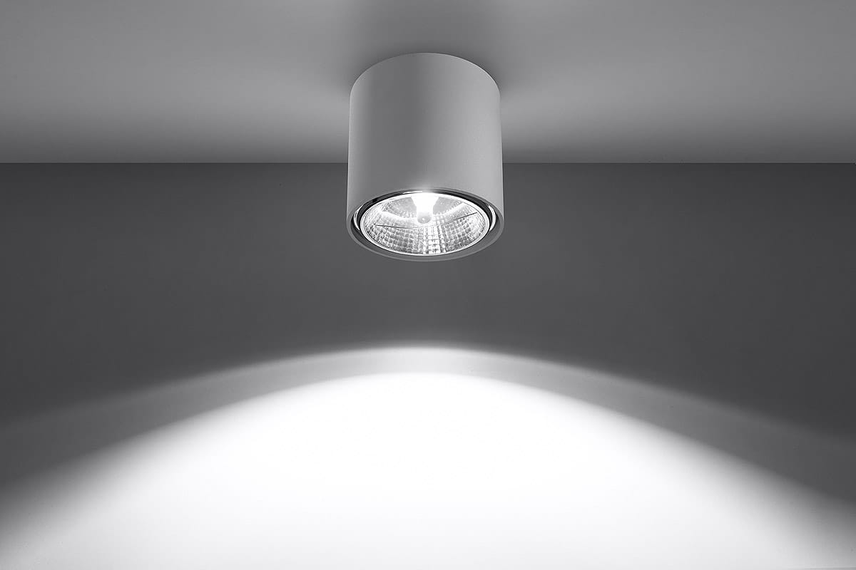 Biała lampa sufitowa 1-punktowa Tiube SL.0695, montowana pod sufitem, o cylindrycznym kształcie. Wyposażona w szklaną osłonę na żarówkę, emitującą światło w dół. Tło jasnoszare, z delikatnymi cieniami na ścianie.