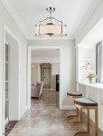 Lampa wisząca Stanza Cromo S w kolorze chromu, z trzema punktami świetlnymi, z okrągłym abażurem w odcieniu kremowym. Zawieszona na metalowym stelażu, z eleganckimi detalami, w nowoczesnym wnętrzu z jasnymi ścianami i podłogą w kolorze beżowym.
