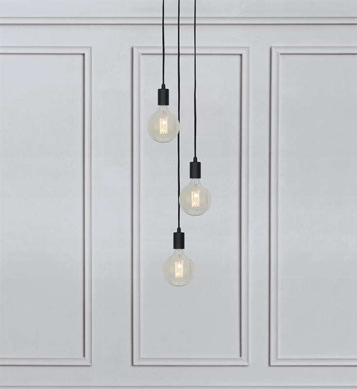 Lampa wisząca Sky 3-punktowa w kolorze czarnym, zawieszona na trzech czarnych linkach. Szklane klosze w kształcie kul, z widocznymi żarówkami, wisi na tle jasnej, gładkiej ściany.