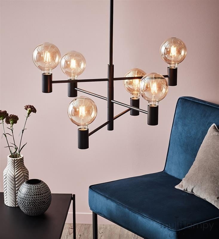 Lampa wisząca Capital w kolorze czarnym, sześciopunktowa, z przezroczystymi kloszami, zawieszona nad niebieskim fotelem. W tle widoczna ściana w odcieniu różowym oraz dekoracyjne elementy, takie jak wazon i kwiaty.