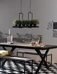 Czarna lampa wisząca Tray LED 3-punktowa, zawieszona nad drewnianym stołem. W lampie umieszczone są doniczki z roślinami. W tle widoczna ściana z szaro-białymi detalami oraz elementy aranżacji, jak świecznik i owoce na tacy.