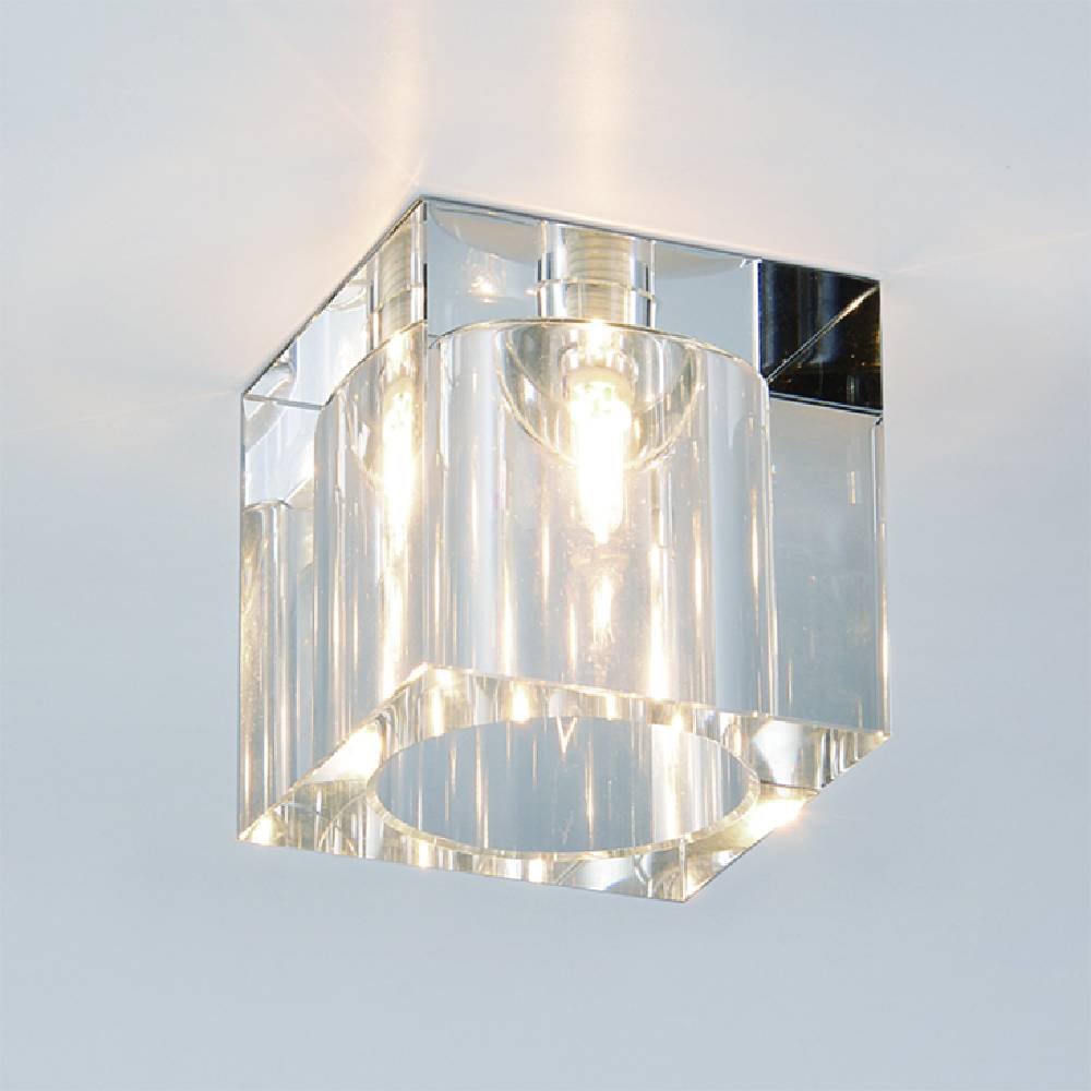 Lampa sufitowa Cubo 1-punktowa o kwadratowej, przezroczystej obudowie z akrylu. Ujęcie z góry, pokazujące źródło światła wewnątrz. Krawędzie lampy są błyszczące, a wnętrze odbija światło, tworząc efektowną iluminację.