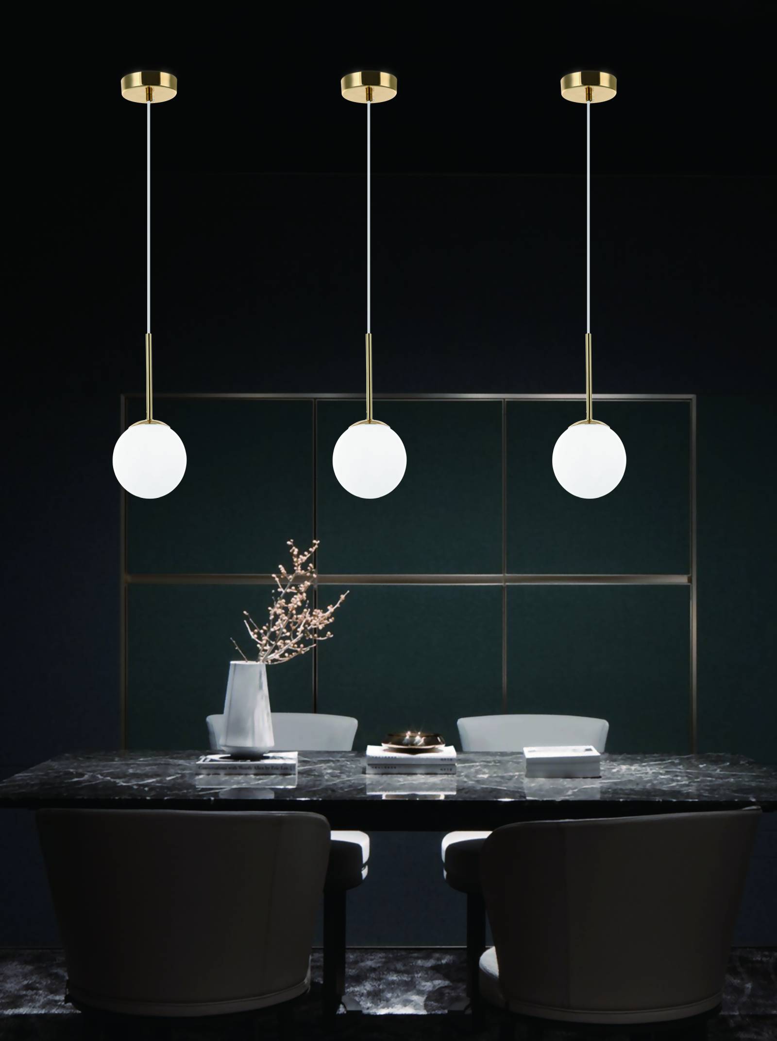 Lampa wisząca Bao I Gold z jednym punktem świetlnym, z okrągłą, białą szklaną kopułą na złotym, metalowym mocowaniu. Zawieszona na cienkim, białym przewodzie. Ujęcie frontalne, w nowoczesnej aranżacji stołu z marmurowym blatem i jasnymi krzesłami.