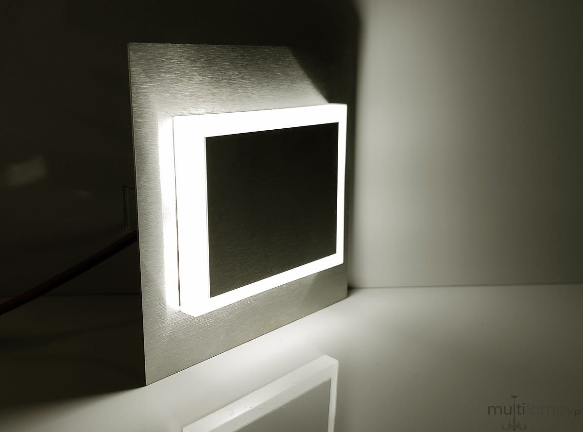Oprawa schodowa Deco LED 230V w barwie neutralnej 4000K, z metalową ramką w kolorze srebrnym i prostokątnym, podświetlonym brzegiem. Ujęcie z boku, ukazujące detal i fakturę powierzchni. Idealna do oświetlenia schodów lub korytarzy.