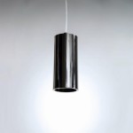 Lampa wisząca Kika S 120 w kształcie cylindrycznym, wykonana z błyszczącego, metalicznego materiału. Zawieszona na przezroczystym przewodzie, emitująca światło z otworu na dole. Tło jasne, minimalistyczne.