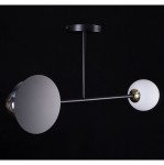 Czarna lampa sufitowa Minerva 2-punktowa z metalowym stelażem, z okrągłymi kloszami: jeden matowy biały, drugi przezroczysty. Zawieszona pionowo na czarnym tle, z widocznym złotym elementem przy mocowaniu.