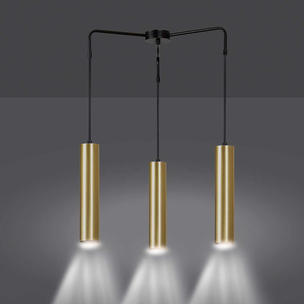 Lampa wisząca Goldi Premium 3-punktowa w kolorze czarnym z trzema cylindrycznymi, złotymi kloszami. Produkt zawieszony na cienkich przewodach, emitujący światło w dół. Tło szare, minimalistyczne.