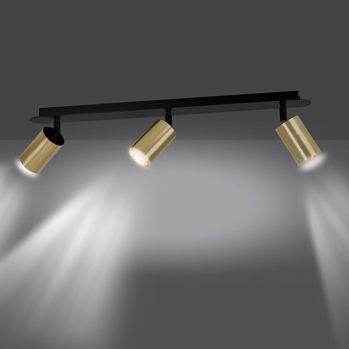 Czarna lampa sufitowa typu spot z trzema złotymi reflektorami. Reflektory umieszczone na prostokątnej, czarnej podstawie, skierowane w różnych kierunkach. Lampa montowana sufitowo, elegancki design, idealna do nowoczesnych wnętrz.