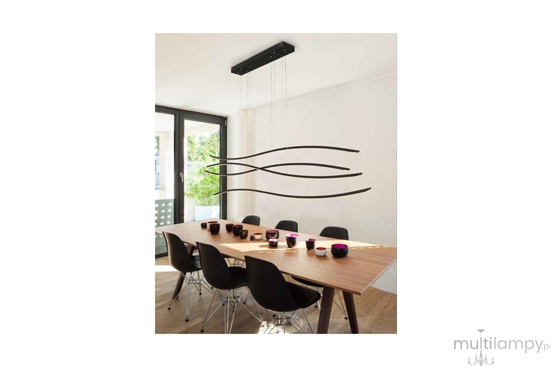 Czarna lampa wisząca LED Waves 4-punktowa z minimalistycznym designem, zawieszona nad drewnianym stołem w jasnym wnętrzu. Kształty lampy przypominają fale, a w tle widoczne są czarne krzesła i kolorowe kubki.