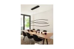 Czarna lampa wisząca LED Waves 4-punktowa z minimalistycznym designem, zawieszona nad drewnianym stołem w jasnym wnętrzu. Kształty lampy przypominają fale, a w tle widoczne są czarne krzesła i kolorowe kubki.