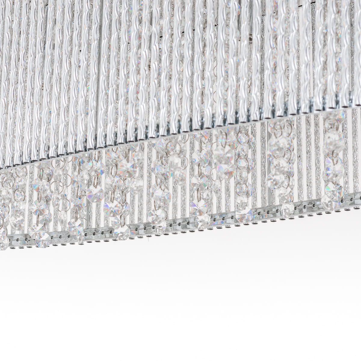 Lampa wisząca Anabella 6-punktowa, z przezroczystymi kryształkami, metalową konstrukcją w srebrnym kolorze. Widoczna górna część z długimi, szklanymi elementami oraz dekoracyjnymi, wiszącymi kryształami. Ujęcie zbliżeniowe na detale.