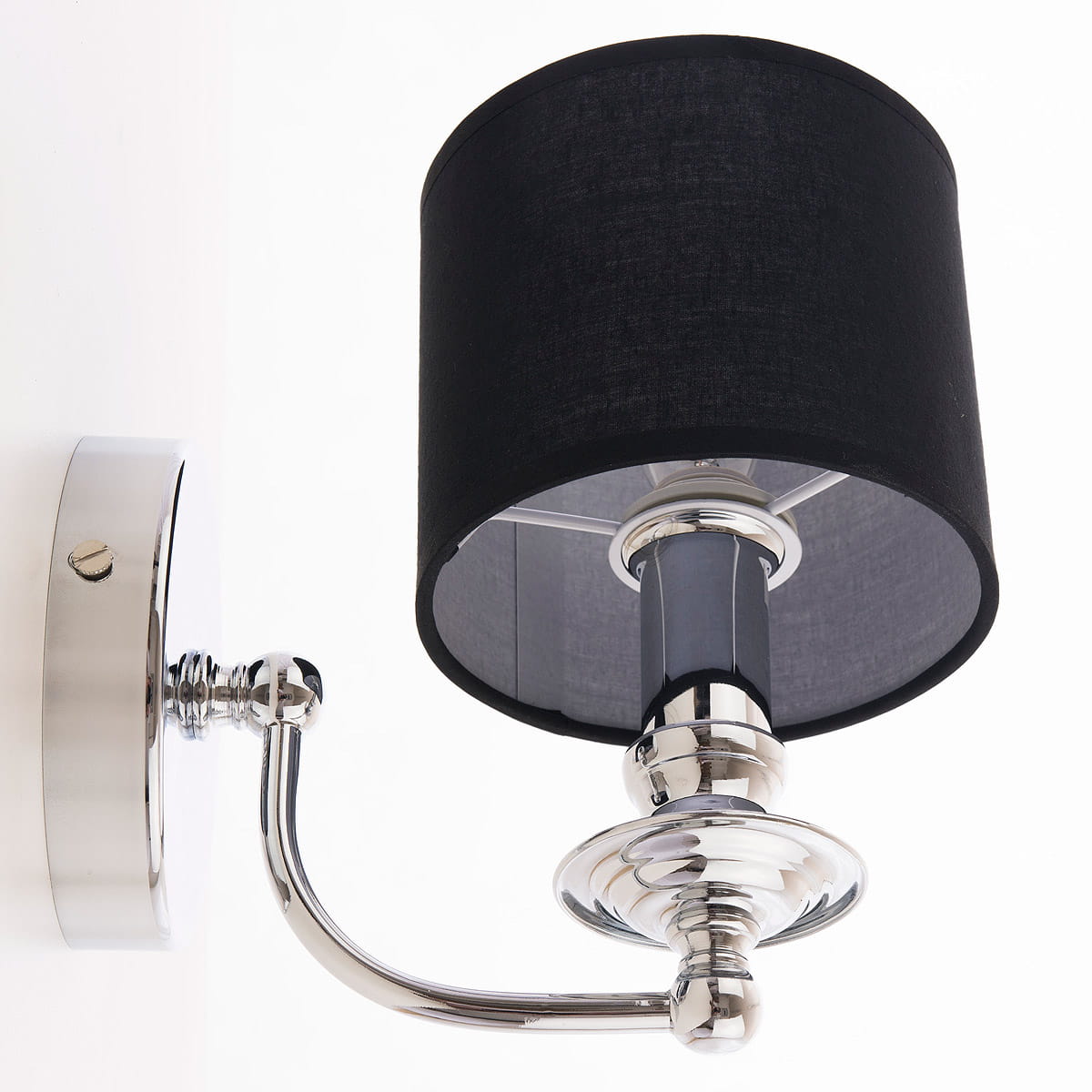 Kinkiet Abu Dhabi 1-punktowy w kolorze chromu i czerni. Posiada cylindryczny klosz z czarnej tkaniny oraz metalową, błyszczącą podstawę. Ujęcie z boku, montowany na ścianie. Widoczny przycisk włącznika.