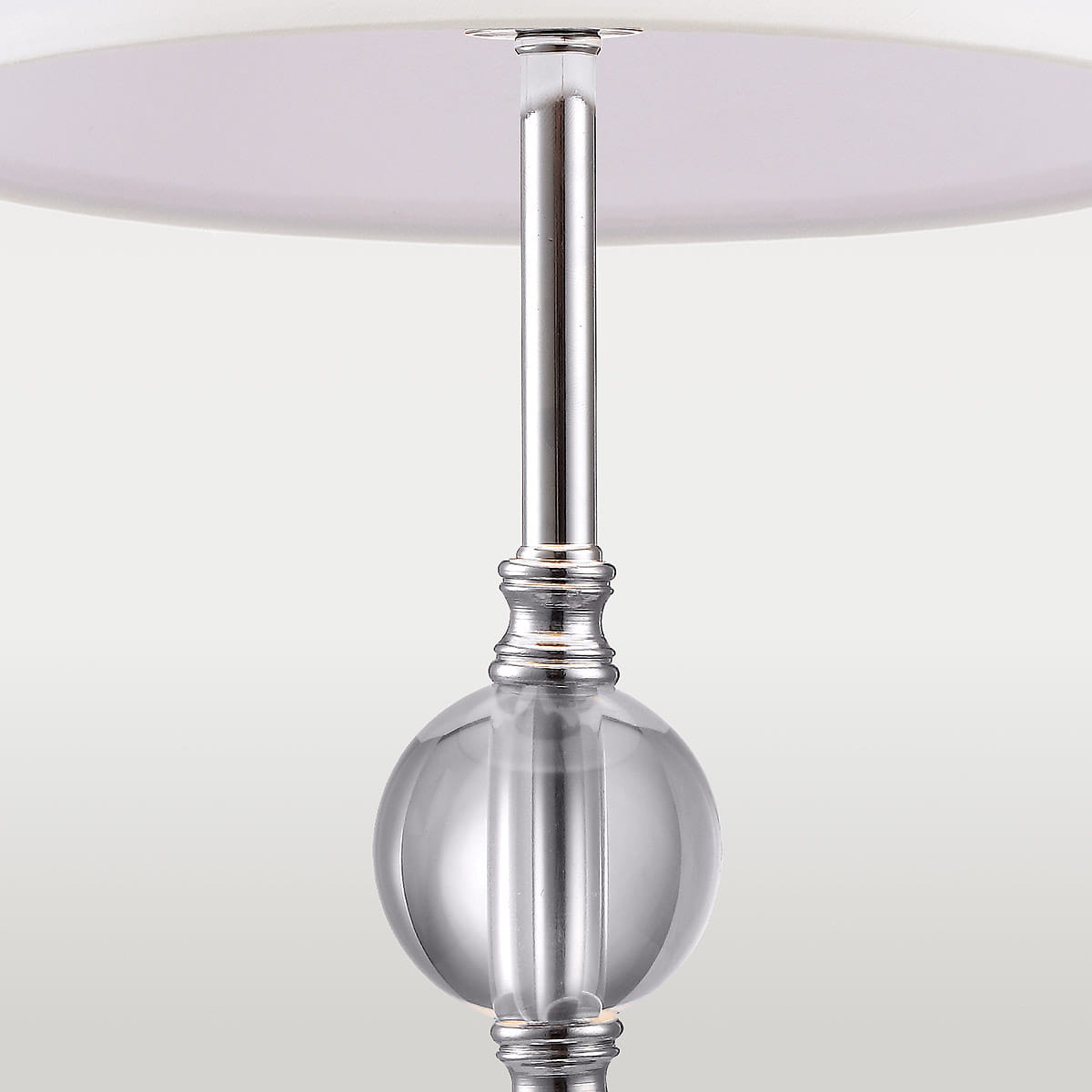 Lampa stołowa Monaco 1-punktowa, z metalowym stelażem w kolorze srebrnym i szklanym, przezroczystym detalem w kształcie kuli. Klasyczny abażur w kolorze białym, umieszczona w pozycji stojącej, z widocznym połączeniem elementów.