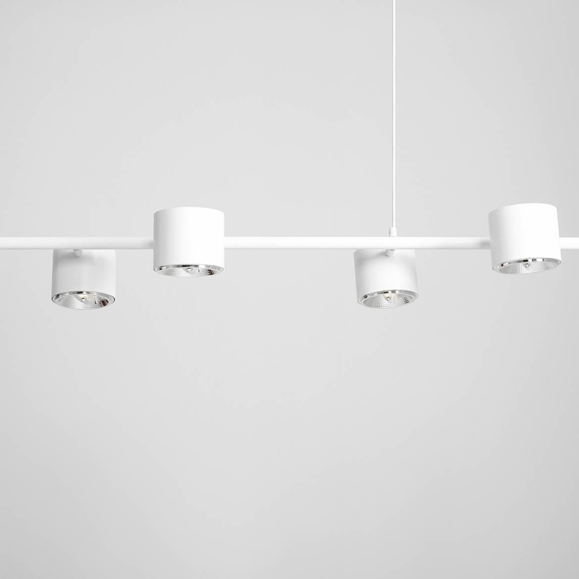 Lampa wisząca Bot 6-punktowa w białym kolorze, składająca się z prostokątnej belki z sześcioma okrągłymi oprawami oświetleniowymi. Ujęcie z góry, ukazujące równomierne rozmieszczenie źródeł światła. Tło jednolite, jasne.