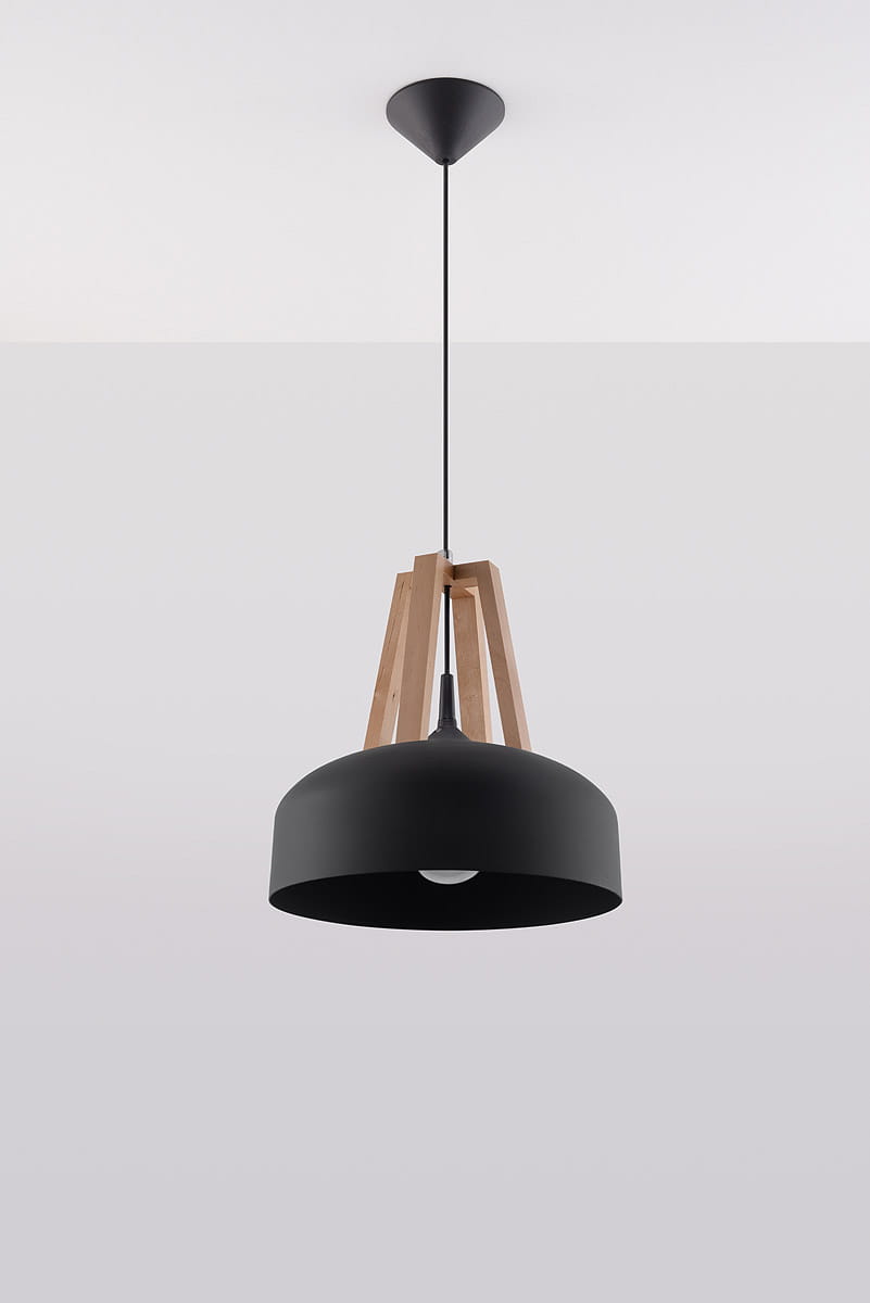 Lampa wisząca Casco 1-punktowa w kolorze czarnym z naturalnym drewnem. Okrągły klosz z matowego metalu zawieszony na cienkim przewodzie, wsparty na trójnogu z drewna. Produkt wisi na prostej, ciemnej podsufitce, na jasnym tle.