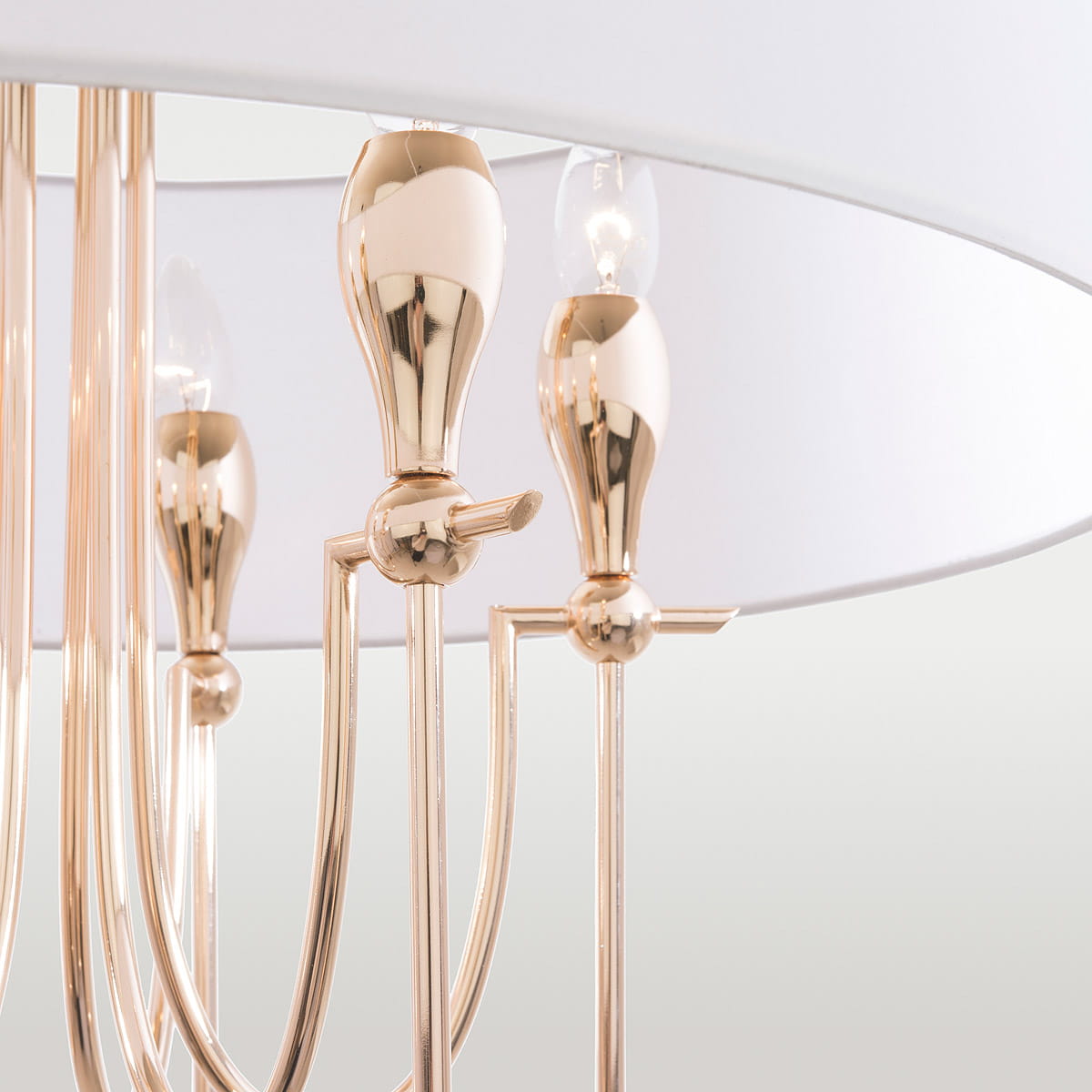 Lampa wisząca Las Vegas, 6-punktowa, w kolorze złotym. Widok z bliska na złote elementy montażowe i klosze, z białym abażurem. Stylowy, elegancki design z subtelnymi detalami. Idealna do nowoczesnych wnętrz.