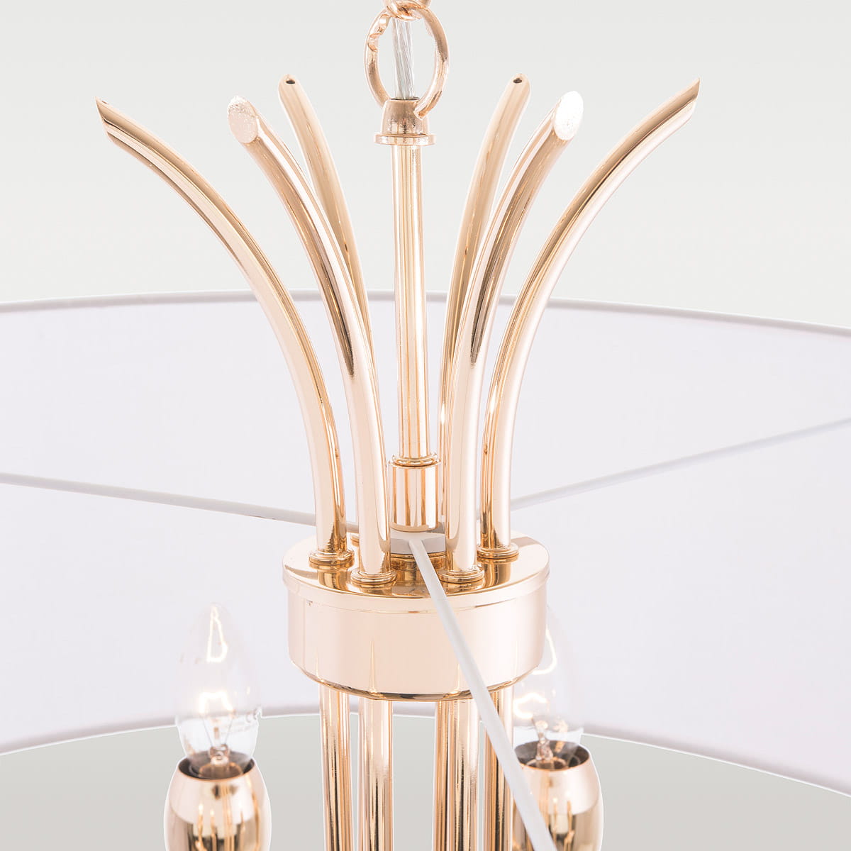 Lampa wisząca Las Vegas 6-punktowa w złotym kolorze, z eleganckimi, zakrzywionymi ramionami i przezroczystymi detalami. Ujęcie z góry, ukazujące mocowanie oraz źródła światła. Okrągły kształt z białym kloszem, umieszczona w minimalistycznym otoczeniu.