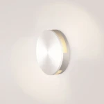 LED oprawa schodowa Lesel 004 w okrągłym, metalicznym wykończeniu. Montowana na ścianie, emituje ciepłe światło przez wąski pasek. Prosty, minimalistyczny design, idealna do oświetlenia korytarzy i schodów.
