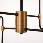 Lampa wisząca Boston 8-punktowa, z metalowym, złotym korpusem i czarnymi ramionami. Ujęcie z bliska na centralny element oraz połączenia, ukazujące prostą, industrialną formę i nowoczesny design.