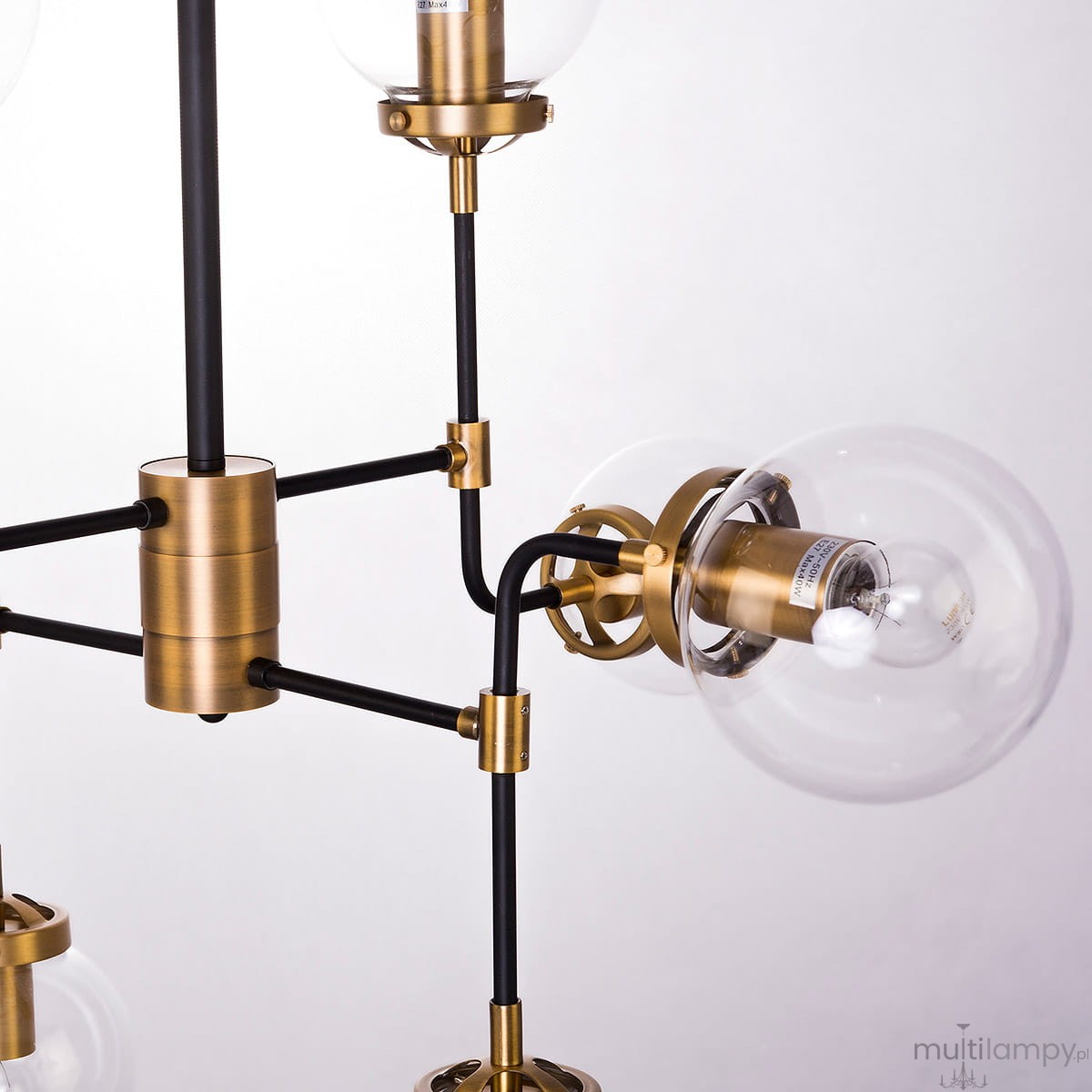 Lampa wisząca Boston 8-punktowa, złoty metalowy stelaż z czarnymi rurkami, przezroczyste szklane klosze. Ujęcie zbliżeniowe na elementy mocujące i detale konstrukcji.