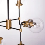 Lampa wisząca Boston 8-punktowa, złoty metalowy stelaż z czarnymi rurkami, przezroczyste szklane klosze. Ujęcie zbliżeniowe na elementy mocujące i detale konstrukcji.