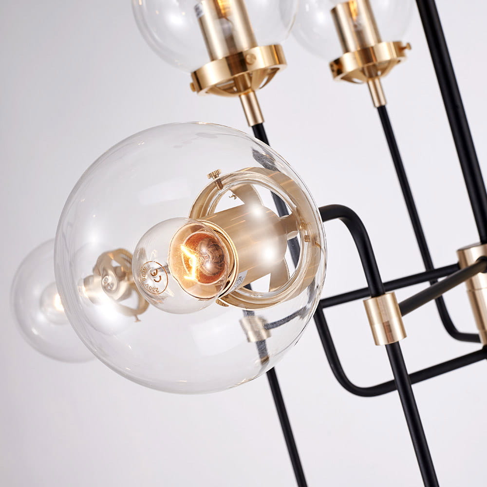 Lampa wisząca Boston 12-punktowa, z czarnymi metalowymi ramionami i przezroczystymi kloszami. Widoczna złota oprawa żarówki, w zbliżeniu na detale konstrukcji. Ujęcie z boku, eksponujące elegancki design.